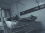 A grainy, blue-tinted, low-light image shows Jessica Lynch lying in a hospital bed prior to her rescue.